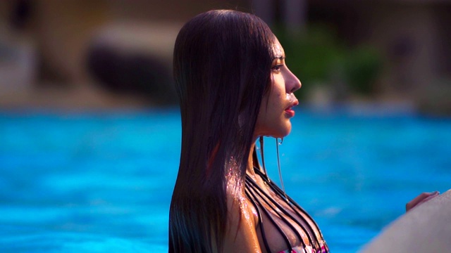 亚洲女人放松在豪华酒店的游泳池享受旅游度假胜地。4 k。视频素材