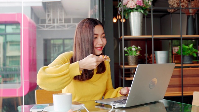 年龄在30-40岁之间的亚洲女性，穿着休闲装坐在咖啡厅或café共同工作空间。视频素材