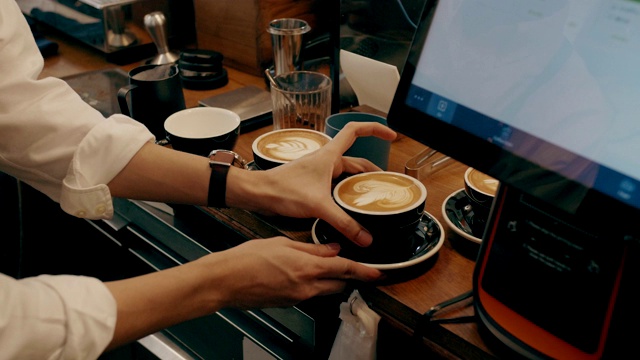 咖啡师将牛奶倒在咖啡杯上，在拿铁咖啡上作画。视频下载