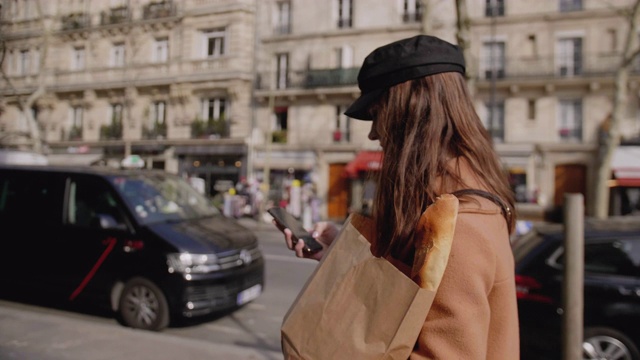 侧视图美丽优雅的美食博主女人走在巴黎街道与生态纸袋慢镜头。视频素材