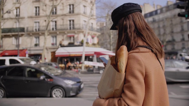 镜头跟随美丽时尚的美食博主女人在网上用手机走在巴黎街头的慢镜头。视频素材
