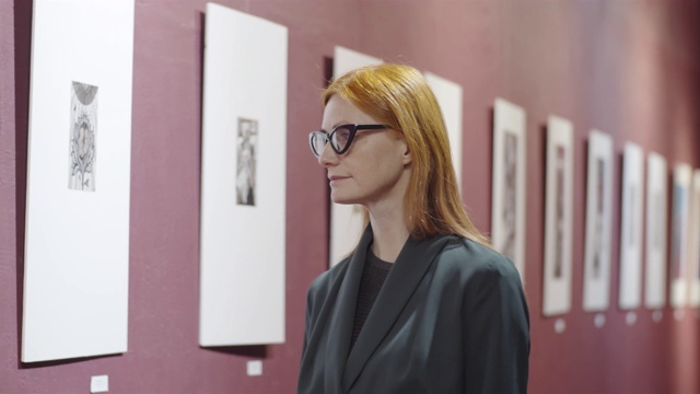 细心的红发女人在画廊看艺术品视频素材