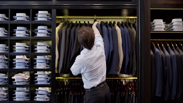 年轻的男性顾客在一家男装店看西装视频下载