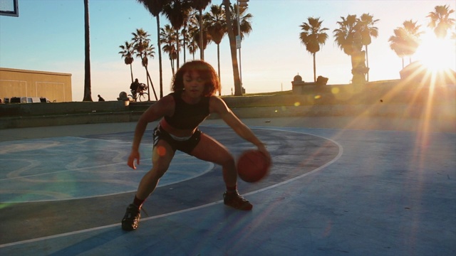 年轻女子在威尼斯海滩球场练习篮球视频下载