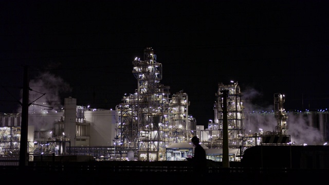 一名男性工程师晚上在照明炼油厂使用平板电脑视频下载