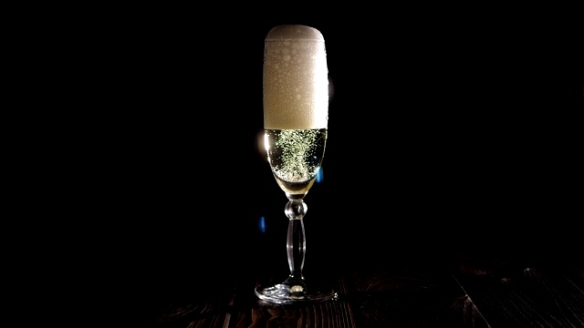 特写的酒保倒香槟到一个杯子上的黑色背景。视频下载
