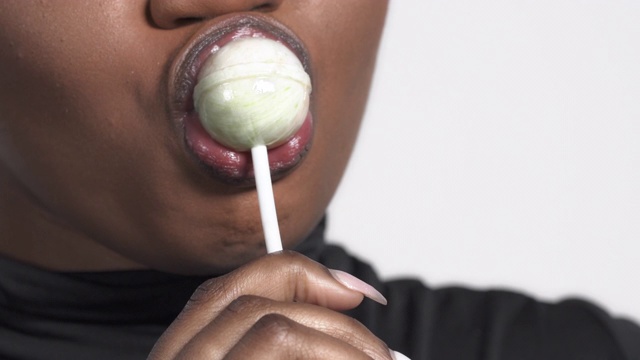 一个迷人的非洲裔美国女人的特写，在她的嘴里有一个棒棒糖视频素材