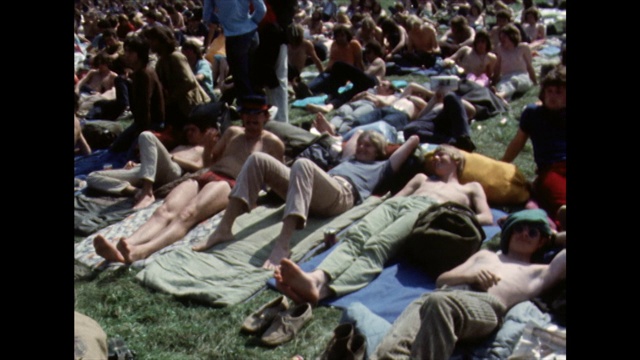 参加节日活动的人们在阳光下坐着等待;1970视频下载