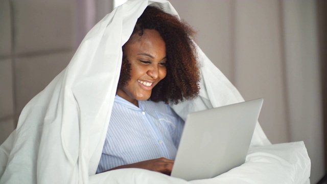 幸福的女人躺在家里的床上视频聊天视频素材