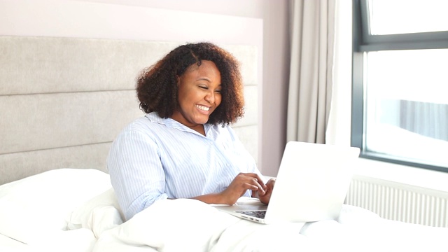 幸福的女人躺在家里的床上视频聊天视频素材