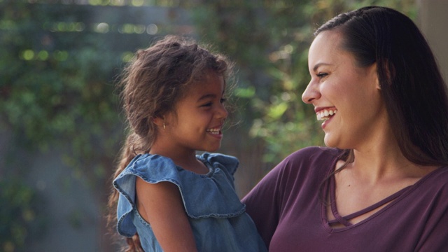 微笑的西班牙母亲和女儿在花园里笑的肖像在家视频素材