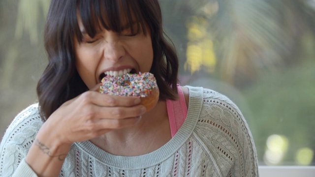 一名年轻女子正在吃甜甜圈视频下载