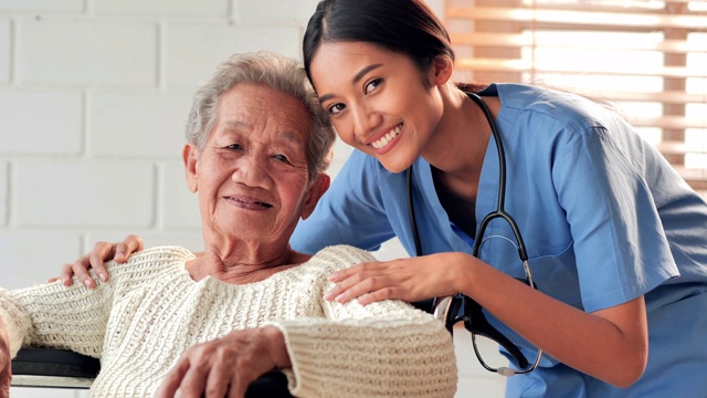 肖像快乐的志愿者年轻的黑人女性护士看护与亚洲老年祖母病人看着相机呆在家里防止新冠病毒或Covid-19的流行。医疗保健，护理，退休，家庭，慈善，养老院。视频下载
