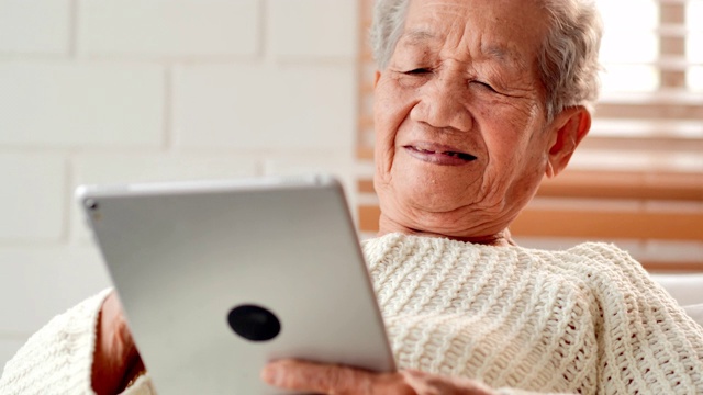 亚洲老年女性患者在家里用平板电脑与医生进行视频会议。老年假期、技术、人、退休、生活方式、全球、医学教育、医疗咨询、医疗保健和医学概念。高级技术视频下载