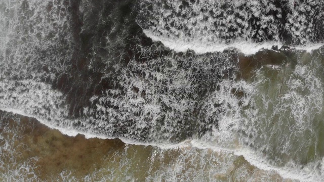 海浪充满藻类和黑色的水流入后的航拍镜头。视频下载