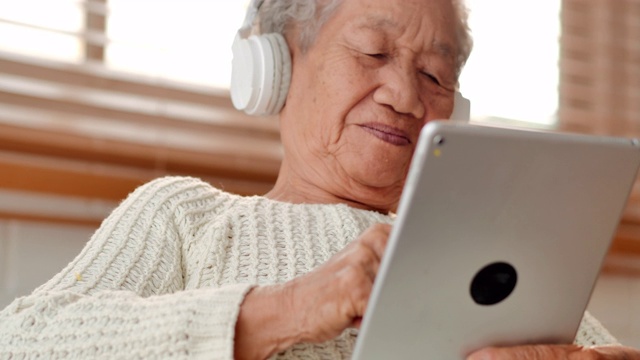 亚洲老年女性患者在家里用平板电脑与医生进行视频会议。老年假期、技术、人、退休、生活方式、全球、医学教育、医疗咨询、医疗保健和医学概念。高级技术视频素材