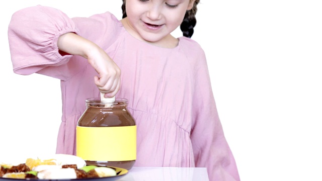可爱的孩子把香蕉浸入巧克力奶油罐中视频素材
