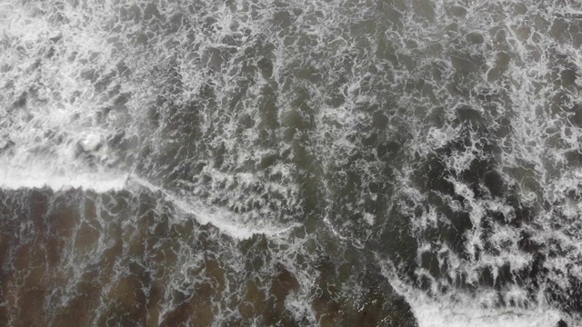 海浪充满藻类和黑色的水流入后的航拍镜头。视频下载
