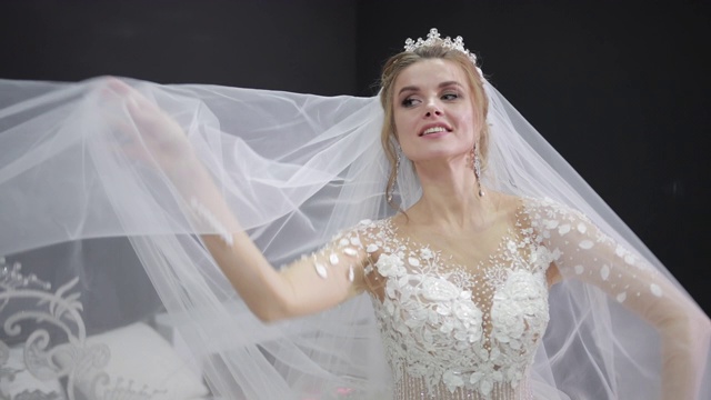 年轻的新娘在白色婚纱玩面纱，使波浪微笑相机视频素材