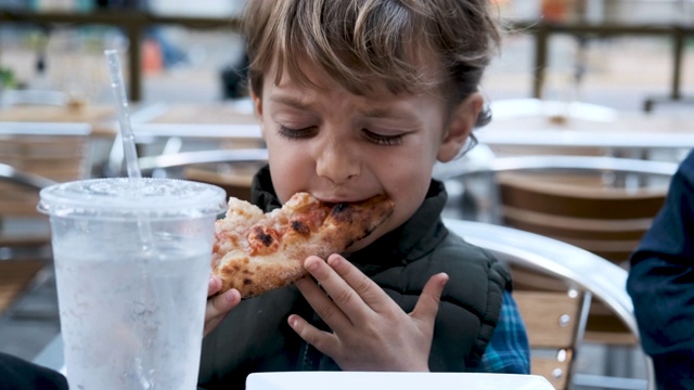 一个小男孩在吃披萨视频素材