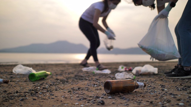 人们在海滩上捡塑料瓶的特写镜头，慢镜头，环境保护视频下载