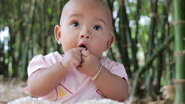 可爱的小亚洲婴儿坐和玩的幸福视频下载