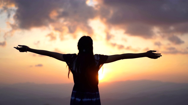 年轻女子在山顶日落做v形手势视频素材