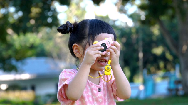 亚洲女孩在户外玩玩具相机视频素材