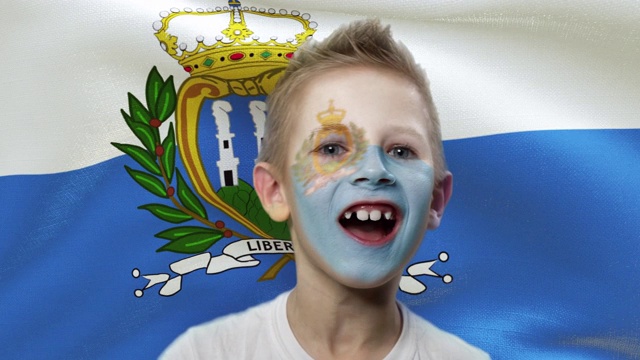 在圣马力诺国旗的背景下，快乐的球迷。快乐的男孩，脸上涂着民族色彩。视频下载