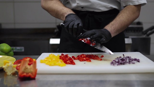 年轻厨师正在餐厅厨房里切红辣椒和洋葱视频素材