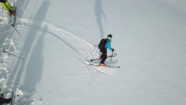 无人机拍摄的一名滑雪者从白雪覆盖的山上滑下来，上面覆盖着新鲜的粉末雪。——慢动作视频素材