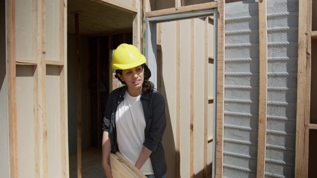 年轻的男建筑工人与女伙伴在建筑工地搬运胶合板视频素材