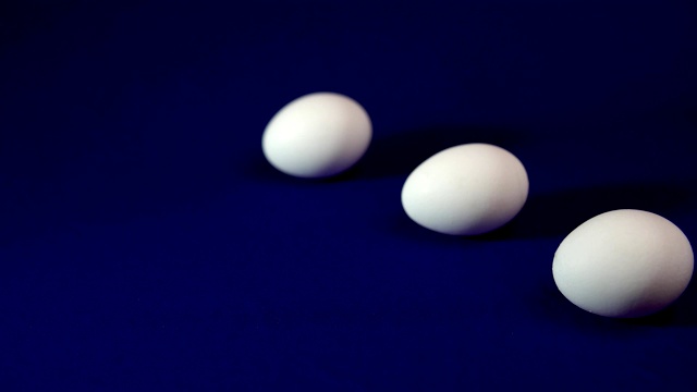 白色鸡蛋的阴影在蓝色背景上移动。视频下载
