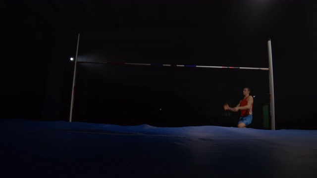 慢动作:男子跳高运动员在聚光灯下的黑暗背景上视频素材
