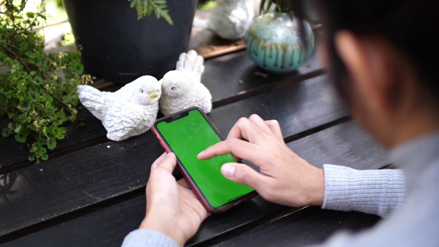 亚洲女性使用绿色屏幕的智能手机视频素材