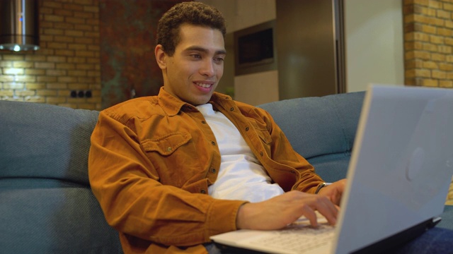成功的年轻人在笔记本电脑上打字和微笑，享受在线交流视频素材
