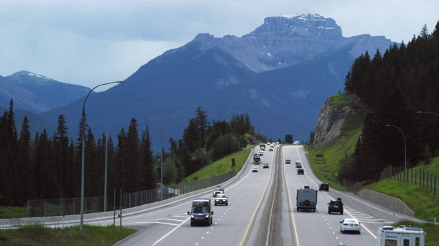 车辆行驶在横跨加拿大高速公路下的阴天与森林和加拿大落基山脉的背景在阿尔伯塔，加拿大视频下载