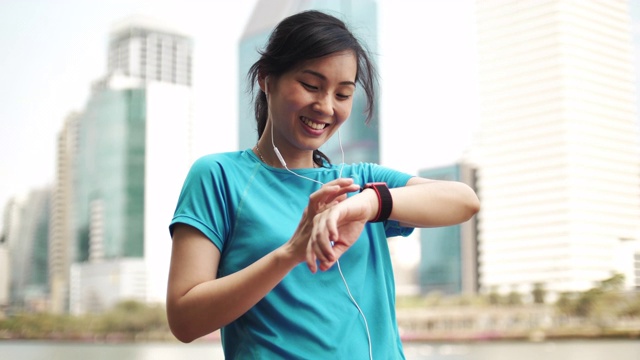 运动亚洲女性使用智能手表在城市视频素材