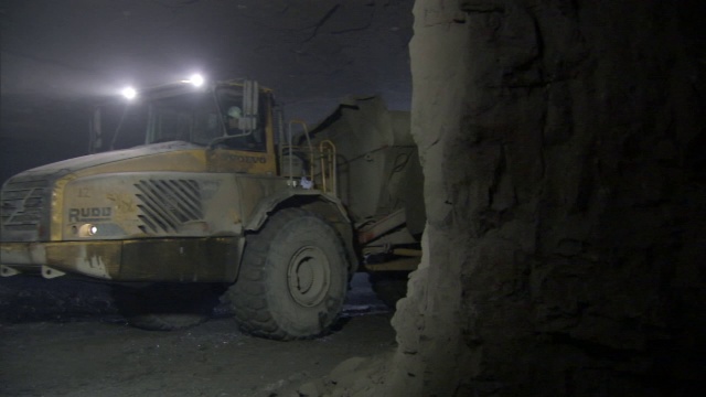 一辆重型采矿拖拉机开过一座铅矿。视频素材