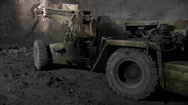 一台配备凿子的挖掘机在矿井壁上挖掘。视频素材