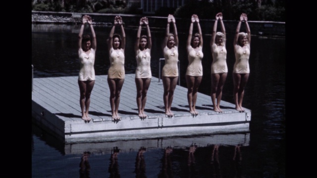 花样游泳队的中景，手臂向上站在湖面上的浮动平台上视频下载