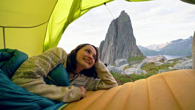 一名妇女躺在Senja岛的帐篷里，可以看到山上的景色视频素材