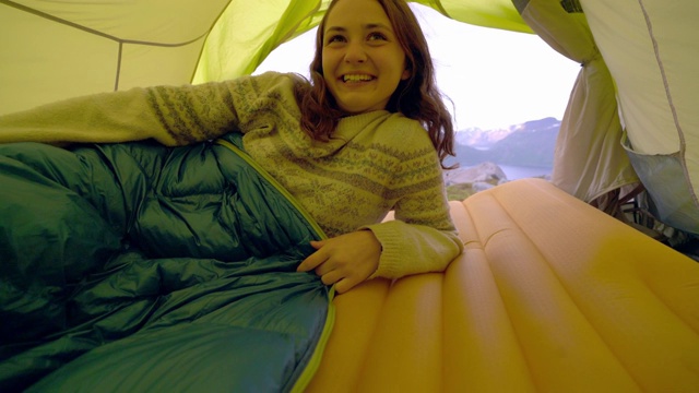 一名妇女躺在Senja岛的帐篷里，可以看到山上的景色视频素材