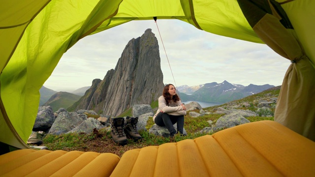 一名妇女坐在山中的Senja岛的帐篷外视频素材