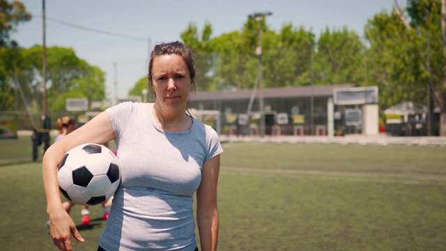 女足球运动员抱着球站在足球场上视频素材
