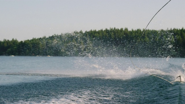 一个阳光明媚的下午，一个20多岁的白人男子在维克特附近的格伦湖上跳起并表演特技视频下载