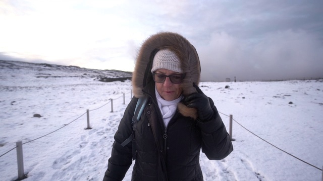 老妇人在冰岛寒风中行走视频素材