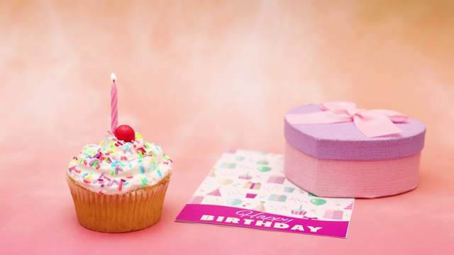 生日派对杯蛋糕与白色奶油和蜡烛出现在桌子上与贺卡和生日礼物-停止运动视频下载