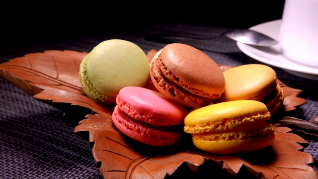 五颜六色的法国马卡龙放在一个棕色的叶子形状的盘子里视频素材