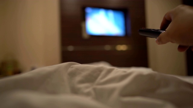 晚上在卧室的床上拿着遥控器和选择香奈儿看电视视频下载